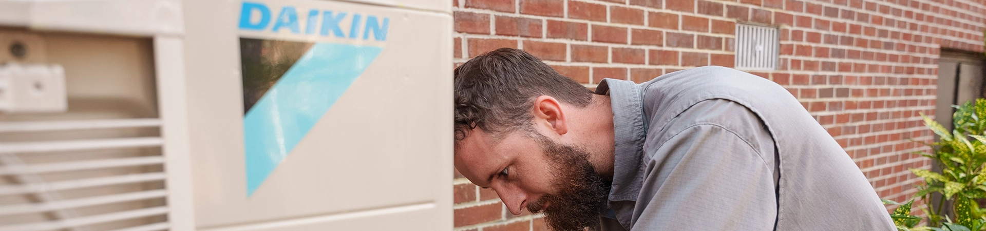 HVAC technician installing a Daikin hvac unit outside a customer's home.